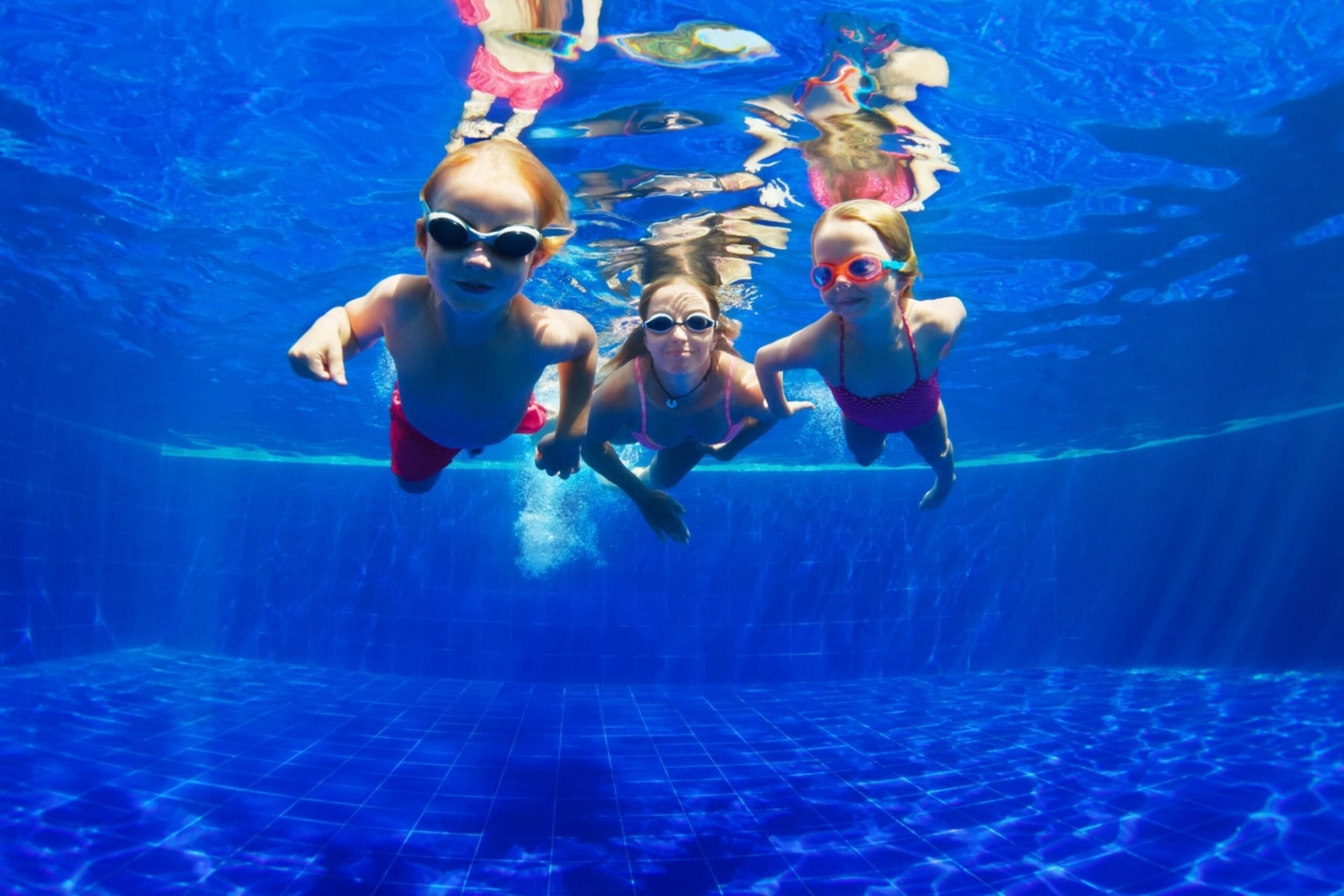 Three kids swimming under the water