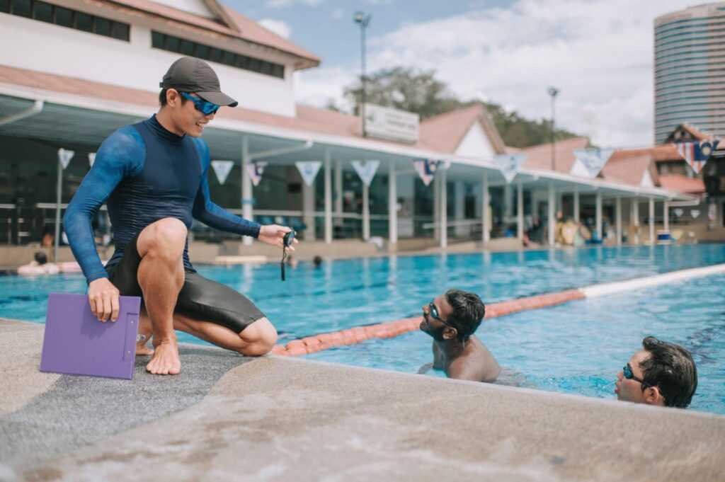 Coach giving some basic swimming guidelines to adult trainees