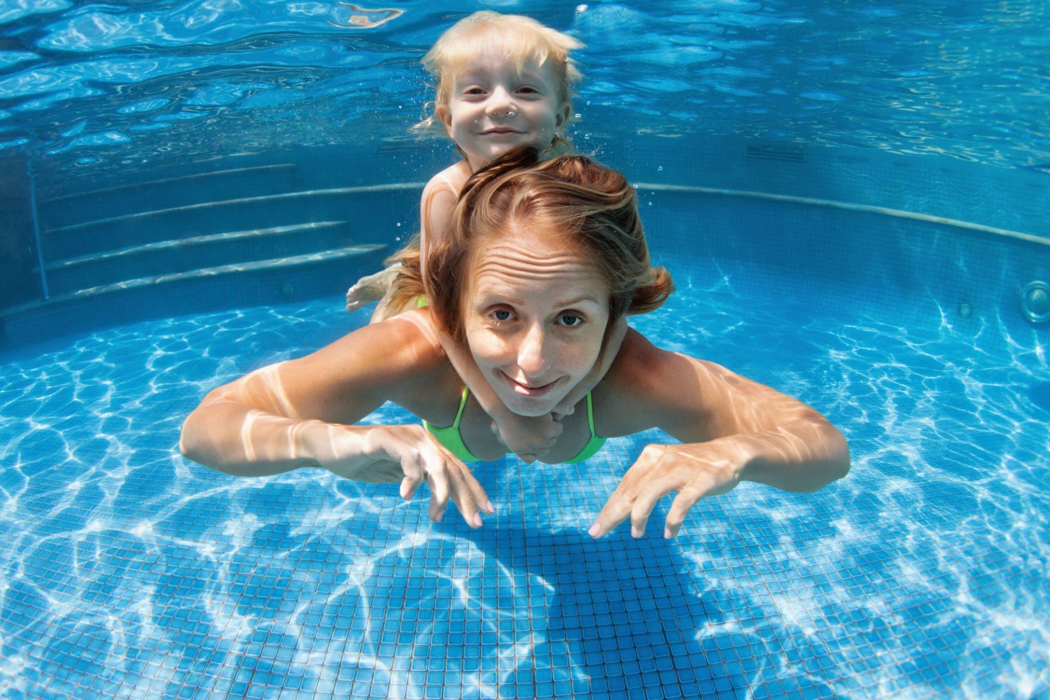 Kid having his underwater swimming session with her private instructor